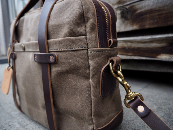 Light brown canvas briefcase measuring 15.5 inches length, 11.75 inches tall and 4.5 inches wide. Dark Brown leather bottom. Two dark brown leather straps riveted to front pocket with copper rivets that becomes the handle. Dark brown leather handle wrap. YKK Brass zipper. Dark brown leather shoulder strap with copper rivets and antique brass swivel snaps.