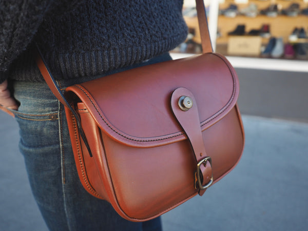 Brown leather purse with flap and leather binding.  Solid brass quick snap and rounded buckle.