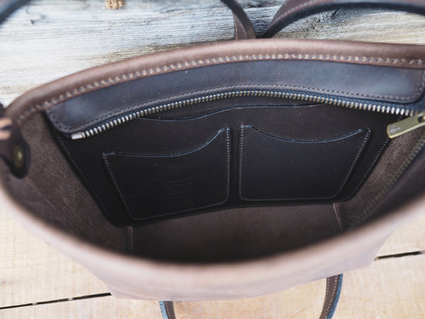 Top of dark brown leather purse.  Brass zipper opened.  Organizer interior pocket with two smaller pockets sewn to organizer pocket.